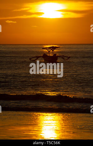 Ein traditionelles balinesisches Fischerboot Jukung bei Sonnenuntergang am Strand Jimbaran, Bali, Indonesien Stockfoto