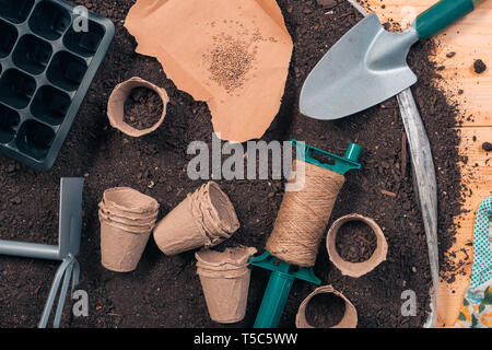 Seeding tomate Ausrüstung und Boden - biologisch abbaubar Karton Töpfe, Gartengeräte und Tomatensamen bereit für die Aussaat, Ansicht von oben flach Stockfoto