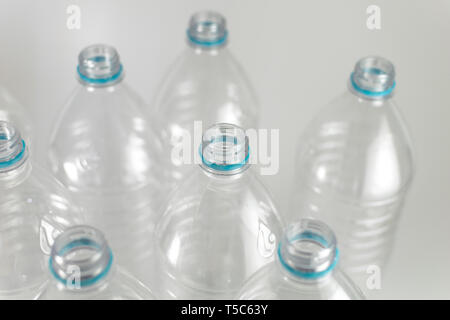 Engpässe einer Packung Liter und eine Hälfte der leeren Mineralwasser ohne Kappen nur mit der blauen Dichtring auf einem weißen Hintergrund. Wiederverwendung, Eco-Friend Stockfoto