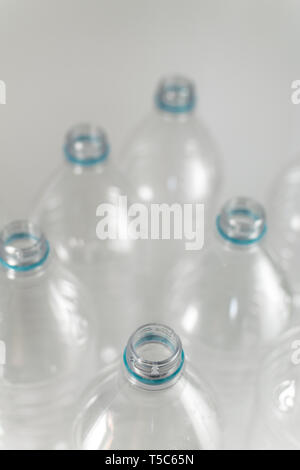 Engpässe einer Packung Liter und eine Hälfte der leeren Mineralwasser ohne Kappen nur mit der blauen Dichtring auf einem weißen Hintergrund. Wiederverwendung, Eco-Friend Stockfoto