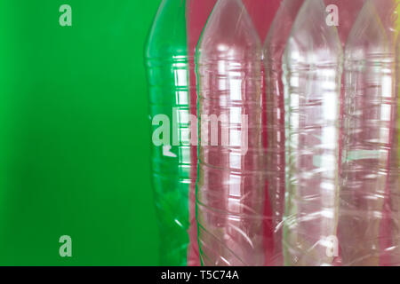 Eine Packung leer und recycelbaren Kunststoff Flaschen mit Wasser, auf einem farbigen leuchtenden grünen und roten Hintergrund. Wiederverwendung, Umweltfreundlich, Umwelt Konzept Stockfoto