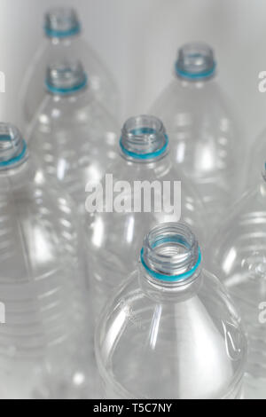 Engpässe einer Packung Liter und eine Hälfte der leeren Mineralwasser ohne Kappen nur mit der blauen Dichtring auf einem weißen Hintergrund. Wiederverwendung, Eco Stockfoto