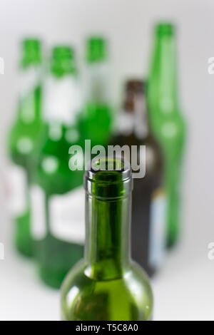 Nahaufnahme von einem Engpass der grüne Wein Glas Flasche ohne Etikett mit mehreren Bier und Wein grünen und braunen Flaschen in der Hintergrund verschwommen Stockfoto