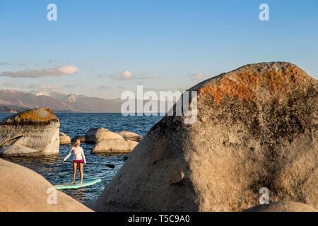 Aktive junge Frau paddleboarding über einen See. Stockfoto