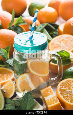 Frische Limonade in einem Glas Becher mit Deckel und einem Einweg-röhrchen auf dem Hintergrund der Frucht Stockfoto
