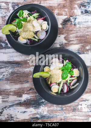 Salat mit Radieschen, Rotkohl, Gurken, Pesto und Sesam. Ansicht von oben Stockfoto