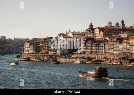 Die Altstadt von Porto am Fluss Douro mit touristischen Boote und Fähren bei Sonnenuntergang, Portugal. Stockfoto