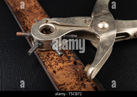 Arbeiten in einem alten Handwerk Werkstatt. Die Löcher in der Haut und anderen Materialien. Der dunkle Hintergrund. Stockfoto