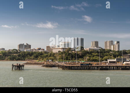 Darwin Australien - Februar 22, 2019: Südseite Downtown Skyline von Hafen Wasser gesehen. Vorne Dock. Blauer Himmel und grünlichen Wasser. Stockfoto