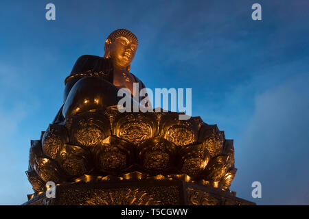 Buddha Statue auf der Oberseite bei Sonnenuntergang in den Wolken. Big Buddha Statue an der Spitze der Fansipan Berg, Sapa, Lao Cai, Vietnam. Spektakuläre Fansipan Legende Stockfoto
