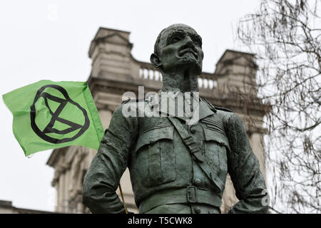 London, Greater London, UK. 23 Apr, 2019. Ian Christian Smuts (Jan Smuts) Skulptur mit einem Aussterben Rebellion Flagge. Aussterben Rebellion Demonstranten März von Marble Arch, Parliament Square, dem Versuch, Briefe an ihre Abgeordneten zu liefern. Aussterben Rebellion Aktivisten waren zulässig im Parlament Platz zu sein, aber das Parlament nicht zu betreten. Nach mehreren Versuchen die Buchstaben zu liefern, die Aktivisten eine Vereinbarung mit MPs durch die Polizei. Zehn Aktivisten wurden erlaubt die Briefe in der Firma der Baronin Jenny Jones (Grüne) liefern. Philosoph und grünen Lager Stockfoto