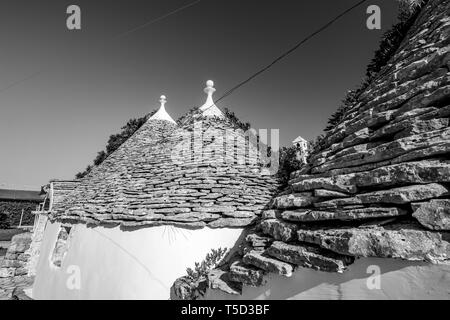 Stadtbild mit typischen herrliche Architektur der truli mit schöne Dächer beleuchtet von der Sonne in Apulien, in der Nähe von Alberobello, Süditalien. Warmen Sommermorgen, Schwarz und Weiß Stockfoto