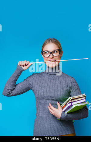 Foto von Lehrerin mit Zeiger in den Mund und Bücher Stockfoto