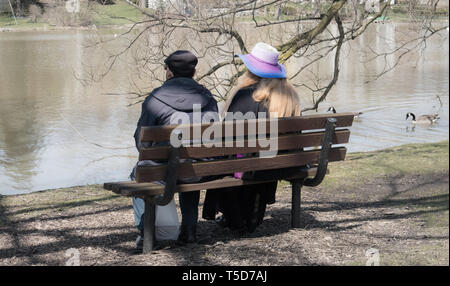 Von hinten gesehen, ein Paar sitzt auf der Bank im Park, mit Blick auf den Lake Victoria. Stratford, Ontario. Stockfoto