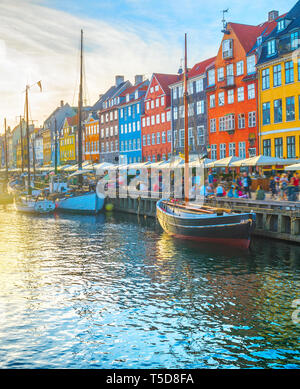 Nyhavn mit Boote von Damm bei Sonnenuntergang, Menschen zu Fuß und Sitzen in Restaurants, Kopenhagen, Dänemark Stockfoto