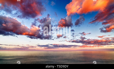 Schönen Sonnenuntergang Wolken über dem Horizont mit Reflexionen Stockfoto