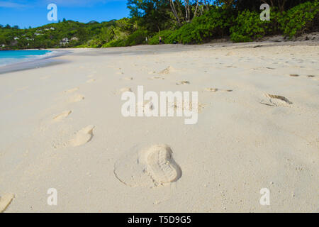 Seychellen leere Küste mit Flip Flop wird gedruckt. Menschlichen Fuß auf Sand. Stockfoto