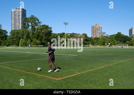 Schwarzer Rüde, Übung mit einem Fußball am Lincoln Park in Chicago. Stockfoto