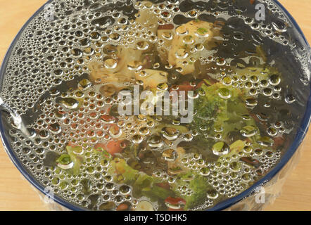 Kondenswasser auf Plastikfolie auf Schüssel pflanzlicher Reste aus dem Kühlschrank genommen für das Abendessen zu erwärmen. Stockfoto