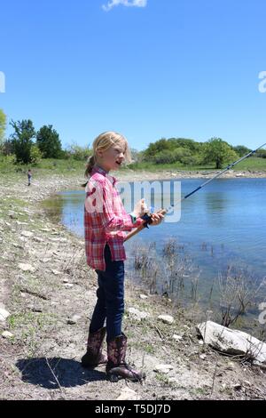 Blonde Mädchen Angeln am Rande eines Wasserlochs Stockfoto