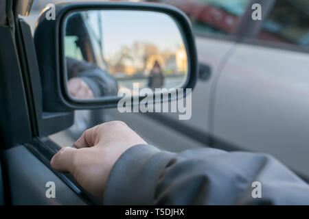 Ein Mann die Hand auf die Autotür auf dem Hintergrund einer weibliche Silhouette im Spiegel der Rückspiegel Stockfoto
