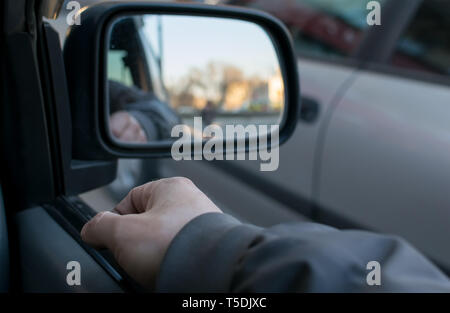 Ein Mann die Hand auf die Autotür auf dem Hintergrund einer weibliche Silhouette im Spiegel der Rückspiegel Stockfoto