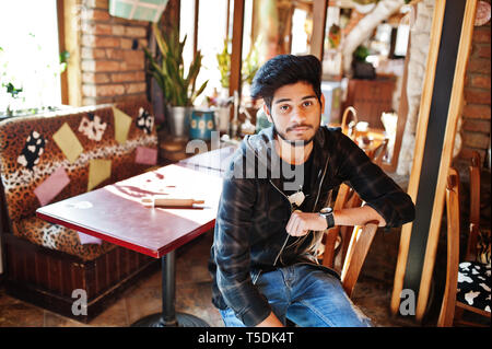 Bart asiatischer Mann in Freizeitkleidung sitzt Innen- Cafe. Stockfoto