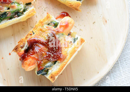 Spinat überbacken mit Käse, Wurst auf Baguette, Französisches Brot Stockfoto