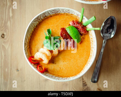 Tom Yam kong Ready-to-eat. Tom Yum Suppe mit Garnelen auf hölzernen Tisch. Beliebte würzige Thailändisches Gericht Tom Yam Ansicht von oben. Thailand Essen und thailändische Küche. Tageslicht Stockfoto