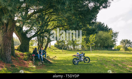 Junges Paar ausruhen von einem Motorrad Reise mit einem Bier im Freien Stockfoto