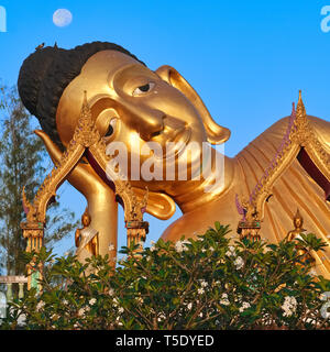 Früh am Morgen, der Vollmond über dem Kopf der großen liegenden Buddha von Wat Sri Sunthorn (Soonthorn) in Thalang, Phuket, Thailand gesehen Stockfoto