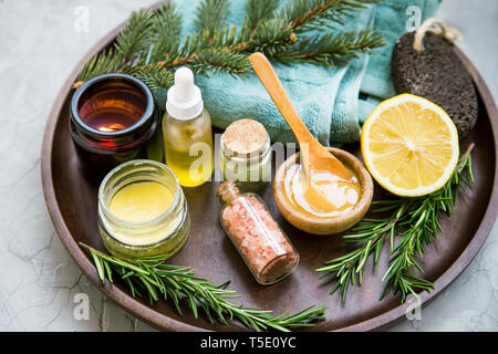 Natürliche organische spa Zutaten mit Manuka Honig, ätherisches Öl Flasche, Lehmpulver, Badesalz, Baumwolle Handtuch, Zitrone, Rosmarin und Pinie Niederlassungen Stockfoto