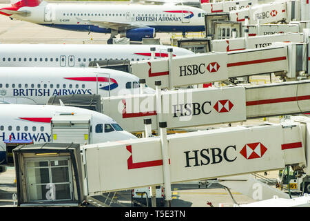 Der Flughafen London Gatwick, ENGLAND - April 2019: British Airways Flugzeuge bis verbunden mit Beifahrer-Brücken die HSBC-Zeichen bei der Gatwick Airport South Stockfoto