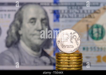 Ein Rubel Münze vor dem Hintergrund von 100 Dollar Banknoten. Stockfoto