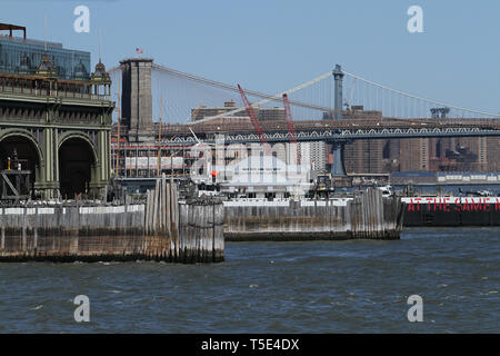 Fähre für die Governors Island, die Manhattan Hubschrauberlandeplatz und der Brooklyn Bridge in der Rückseite gesehen. Lower Manhattan, New York City, USA Stockfoto