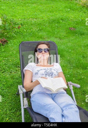 Frau mit einem Buch in einem Liegestuhl Stockfoto