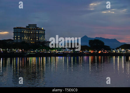 Gebäude entlang Sungai Sarawak (Sarawak River) und Mount Santubong bei Sonnenuntergang, Kuching, Sarawak (Borneo), Malaysia Stockfoto