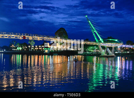 Die Astana (Governor's Palace) und Darul Hana Brücke (Golden Bridge) bei Nacht beleuchtet und reflektiert im Sungai Sarawak (Sarawak River), Pl Stockfoto