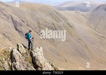 Eine einsame weibliche Wanderer mit den Gipfeln von Kirk fiel und Great Gable, mit schwarzen Segeln, im englischen Lake District National Park, im Hintergrund. Stockfoto