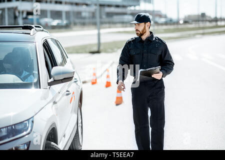 Polizisten zu Fuß zum Stillstand Auto für die Verletzung der Verkehrsregeln auf der City Road Stockfoto