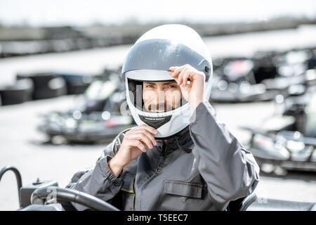 Porträt eines professionellen Racer in Sportkleidung und Helm sitzen im Kart auf der Spur Stockfoto