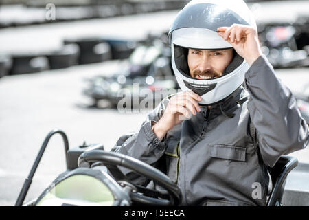 Porträt eines professionellen Racer in Sportkleidung und Helm sitzen im Kart auf der Spur Stockfoto