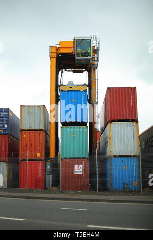 Belfast, County Antrim, Nordirland, 29, März, 2019 - Bunte Container sind, gesehen im Hafen von Belfast, Nordirland Irealnd gestapelt. Straddle Carrier werden am häufigsten für das Stapeln und Verschieben von Containern statt direkt Verladen auf Lkw eingesetzt. Paul McErlane Stockfoto