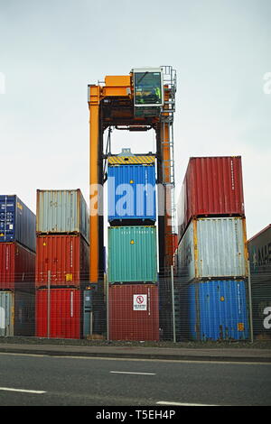 Belfast, County Antrim, Nordirland, 29, März, 2019 - Bunte Container sind, gesehen im Hafen von Belfast, Nordirland Irealnd gestapelt. Straddle Carrier werden am häufigsten für das Stapeln und Verschieben von Containern statt direkt Verladen auf Lkw eingesetzt. Paul McErlane Stockfoto