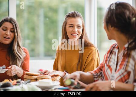 Junge Frau nach einem Gespräch mit Ihrer Freundin, während Sie ein gesundes Mittagessen. Sie sind in einem Wintergarten zu sitzen, sich zu amüsieren. Stockfoto