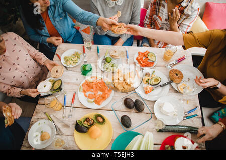 Hohe Betrachtungswinkel und einer kleinen Gruppe von weiblichen Freunden ein gesundes Mittagessen in einem Wintergarten an einem Wochenende vorbereiten. Stockfoto