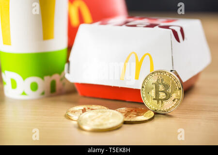 Ljubljana, Slowenien - 27 Dezember, 2018: Big Mac Box mit McDonald's Logo auf Tabelle im McDonald's Restaurant mit Bitcoin Münzen neben Stockfoto