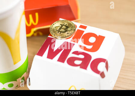 Ljubljana, Slowenien - 27 Dezember, 2018: Big Mac Box mit McDonald's Logo auf Tabelle im McDonald's Restaurant mit Bitcoin Münzen neben Stockfoto