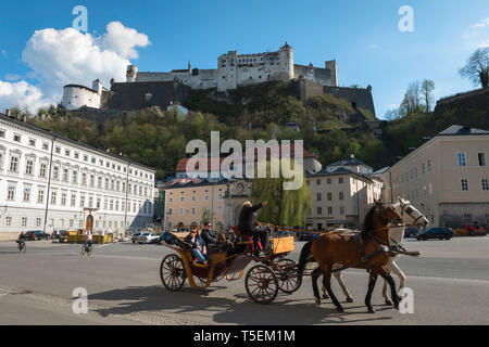 Stadt Salzburg Österreich, Blick auf eine Pferdekutsche durch Kapitelplatz mit Blick auf die Hügel Burg (Festung Hohensalzburg), Salzburg. Stockfoto