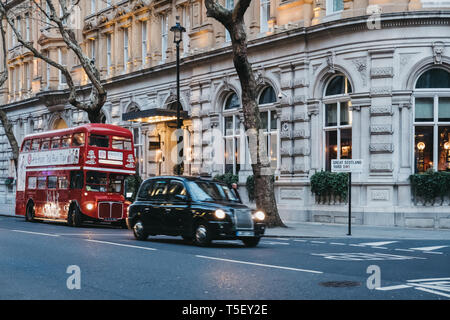 London, Großbritannien, 13. April 2019: Black Cab und einen Tee am Nachmittag Stadtrundfahrt in retro red Double Decker Bus auf einer Straße in London, Großbritannien, in der Dämmerung. Doppel Dez Stockfoto